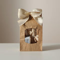 Precious Days Gifts baby bath essentials gift set in a brown paper bag with a cream ribbon bow. Includes washcloths, soap, and a brush.