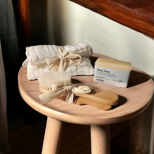 Precious Days Gifts baby bath set with white muslin washcloths, wooden brush and comb, and unfragranced baby soap.