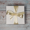 Precious Days Gifts Small New Baby Gift Box with bird rattle, muslin, and teether, tied with a gold ribbon.