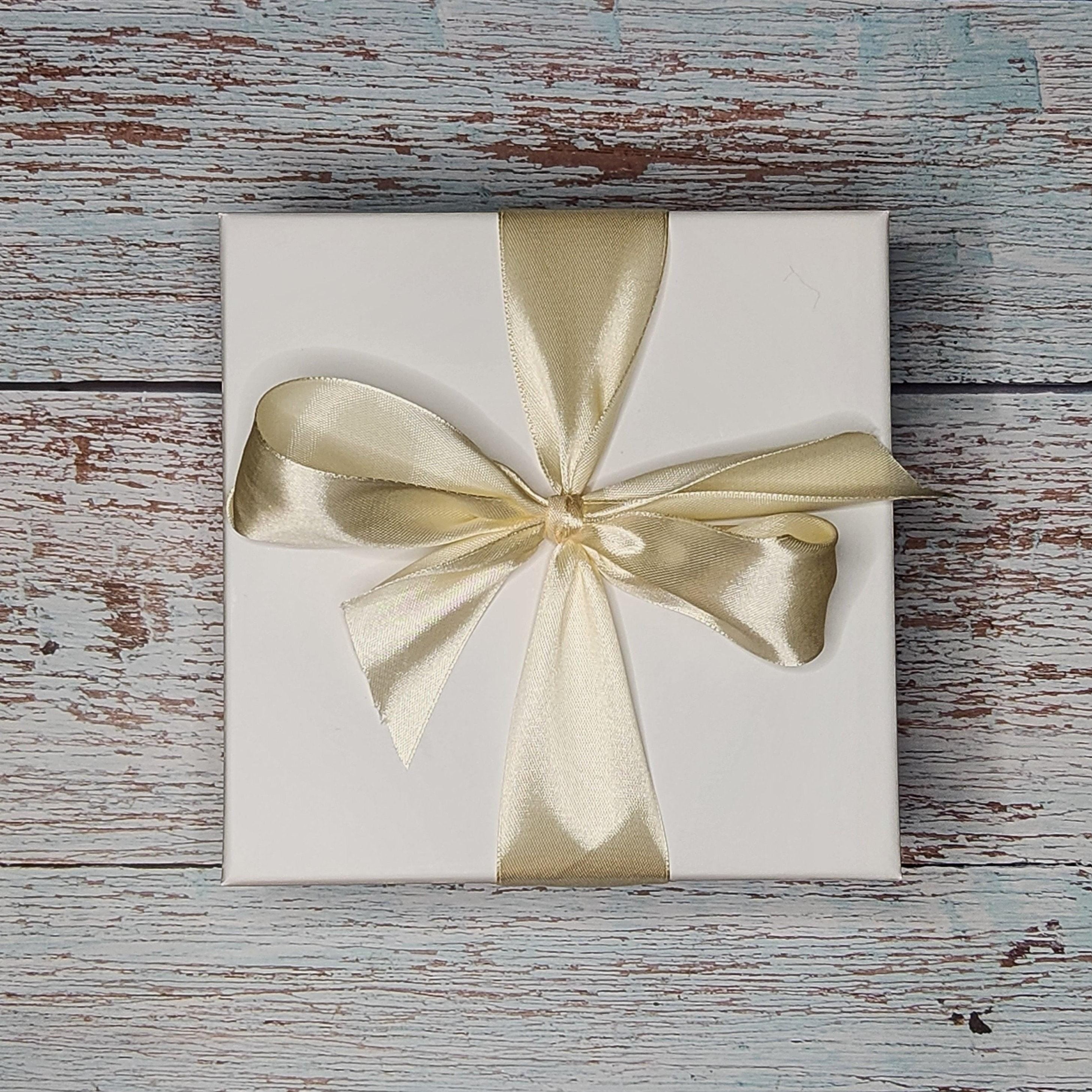 Precious Days Gifts Small New Baby Gift Box with bird rattle, muslin, and teether, tied with a gold ribbon.