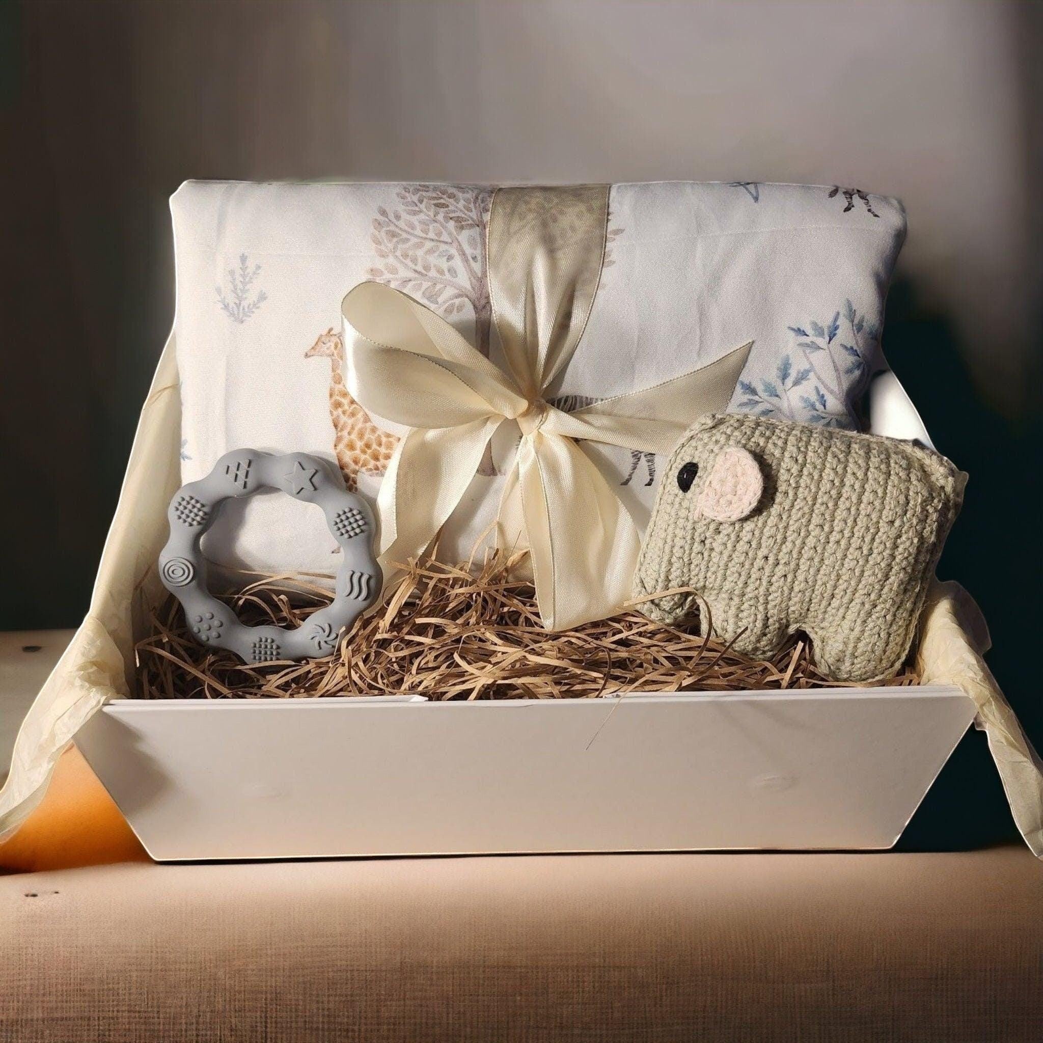 Precious Days Gifts baby gift box with giraffe print blanket, grey teether, and knitted elephant rattle.