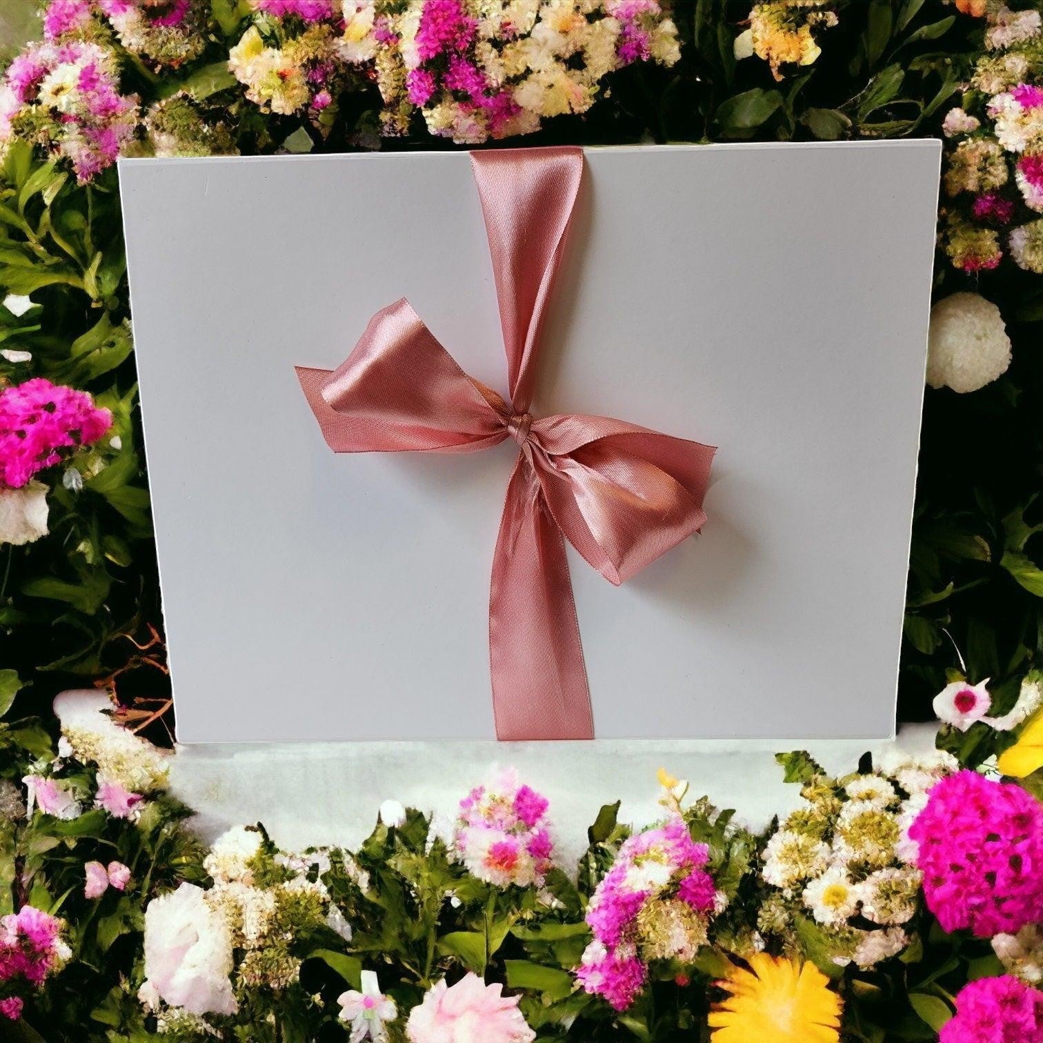 Precious Days Gifts large white new baby gift box with pink ribbon, surrounded by flowers.