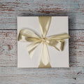 Precious Days Gifts Small New Baby Gift Box: Rainbow, featuring a white box tied with a champagne satin ribbon.