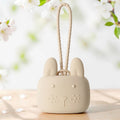 Precious Days Gifts beige silicone bunny storage pouch with a textured wrist strap on a wooden table.