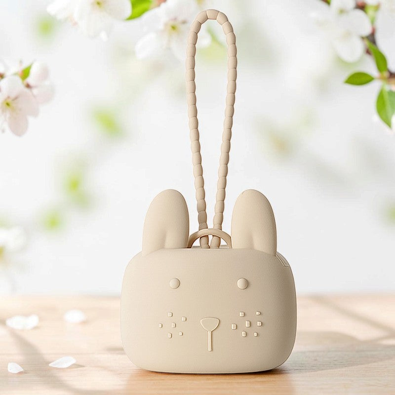 Precious Days Gifts beige silicone bunny storage pouch with a textured wrist strap on a wooden table.