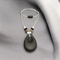 Precious Days Gifts black teardrop silicone teething necklace with leopard print and white beads on a white cord.