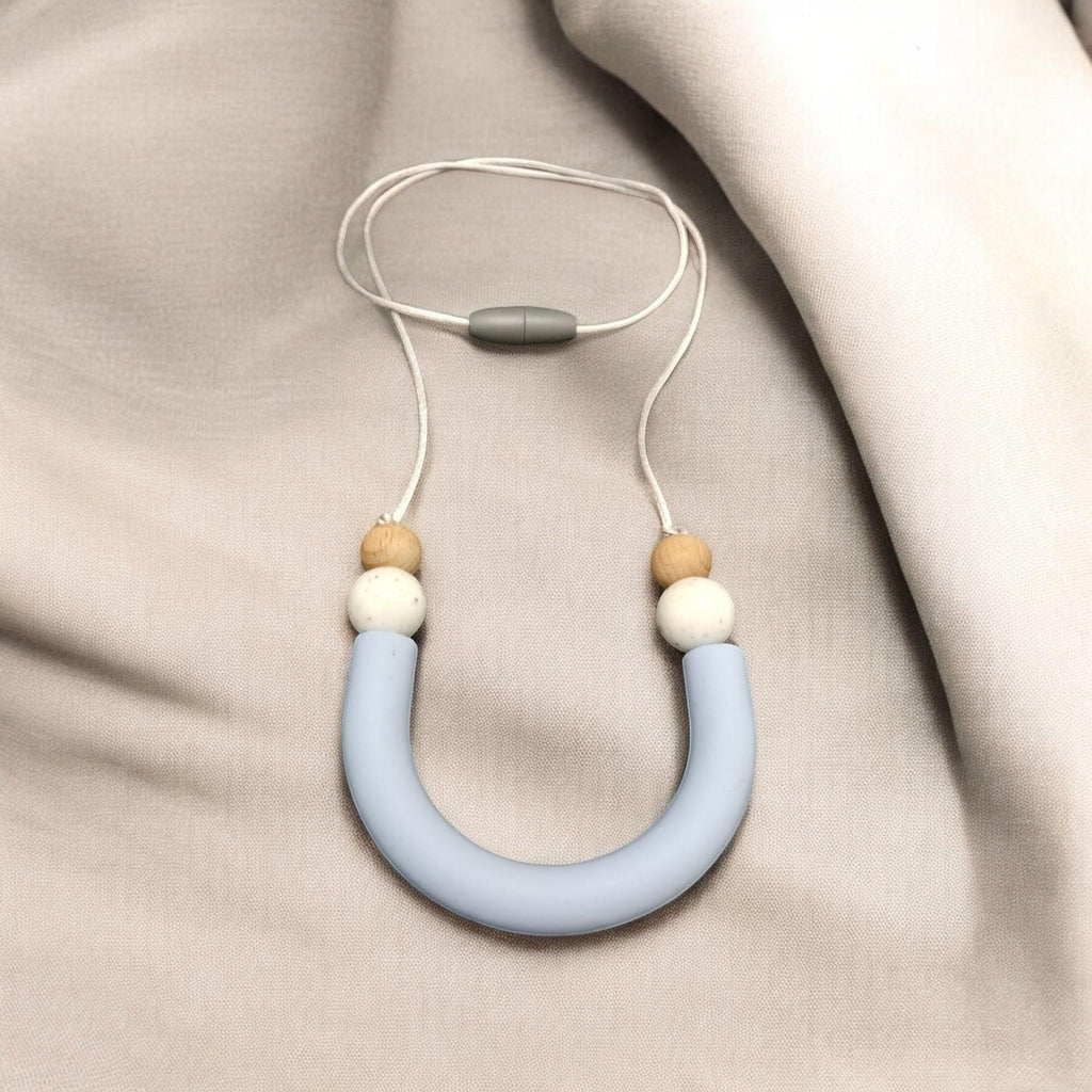 Precious Days Gifts light blue silicone U-shape teething necklace with wood and white beads and a safety clasp.