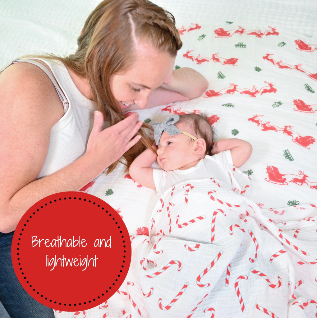 Precious Days Gifts muslin swaddle blanket with candy cane print covering a baby lying next to a smiling mother