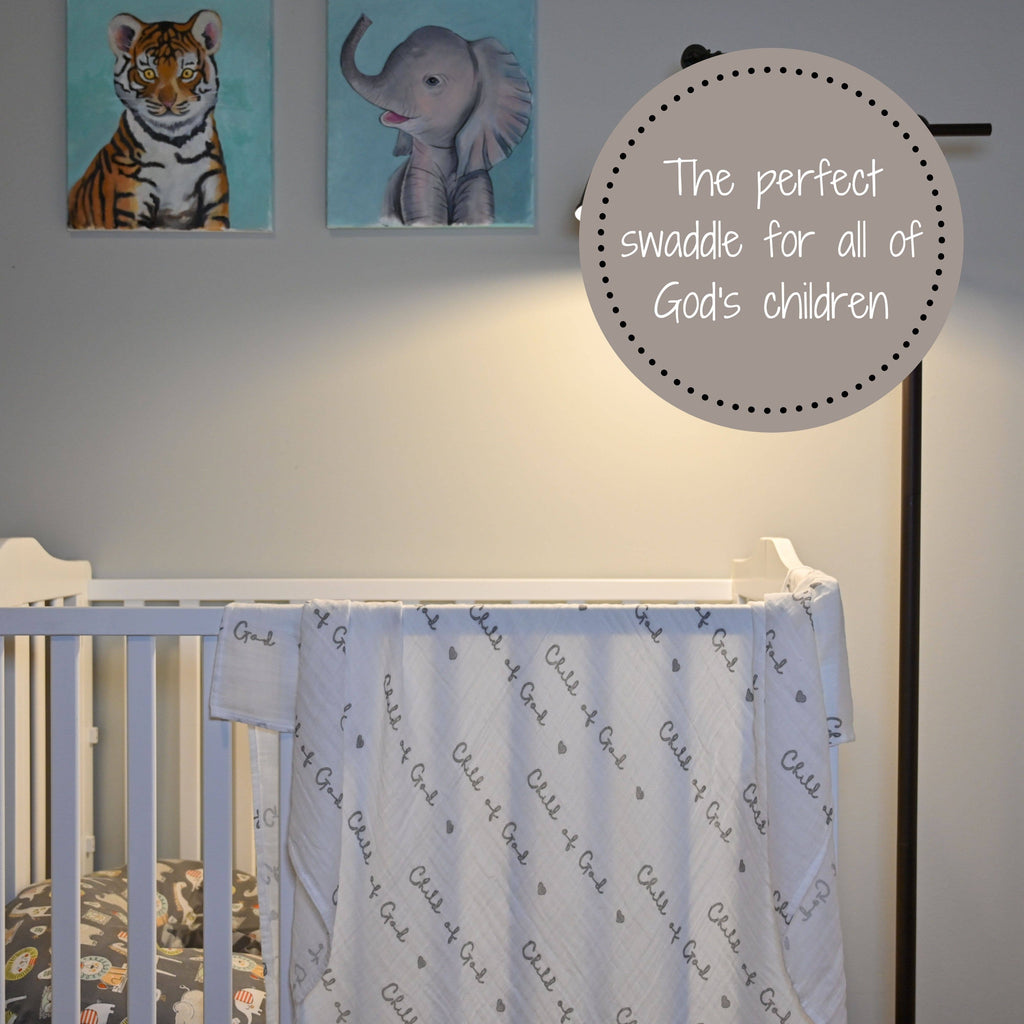 Precious Days Gifts Child of God muslin swaddle blanket draped over a white crib in a nursery with animal art