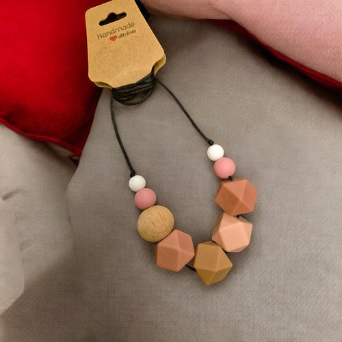 Precious Days Gifts chunky neutral silicone and wood teething necklace for babies. Features geometric and round beads in pink, tan, and white.