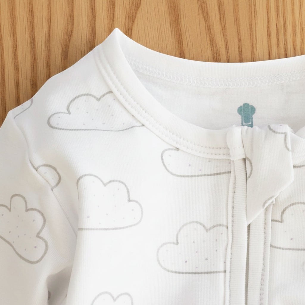 Precious Days Gifts white baby onesie featuring a grey cloud pattern and a soft zip-up neckline.