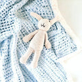 Precious Days Gifts cream crochet bunny rattle on a blue speckled baby blanket