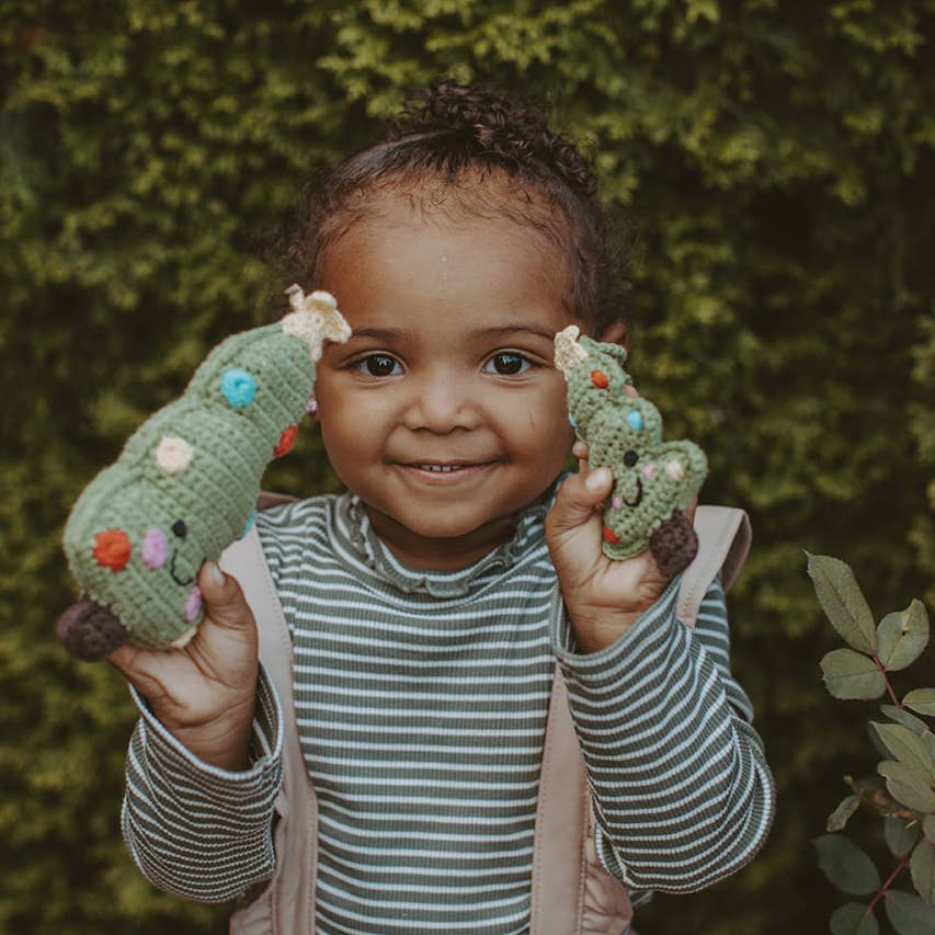 Precious Days Gifts handmade organic cotton Christmas tree rattle held by a smiling toddler in a striped shirt