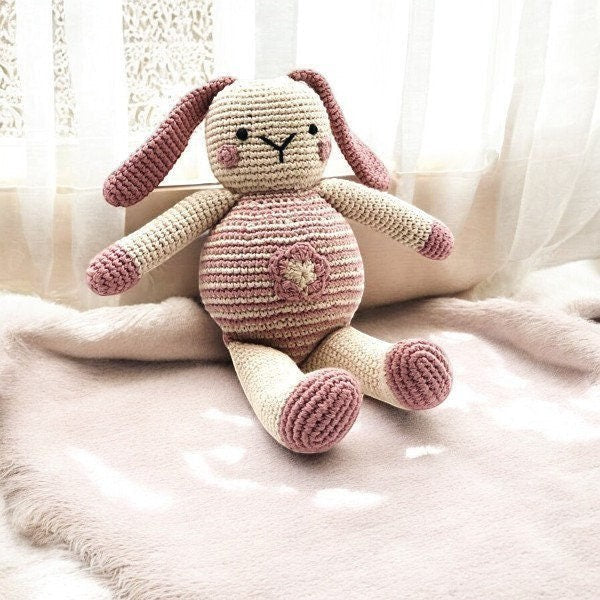 Precious Days Gifts crocheted bunny toy with pink accents and a flower detail on its belly, made of cotton.