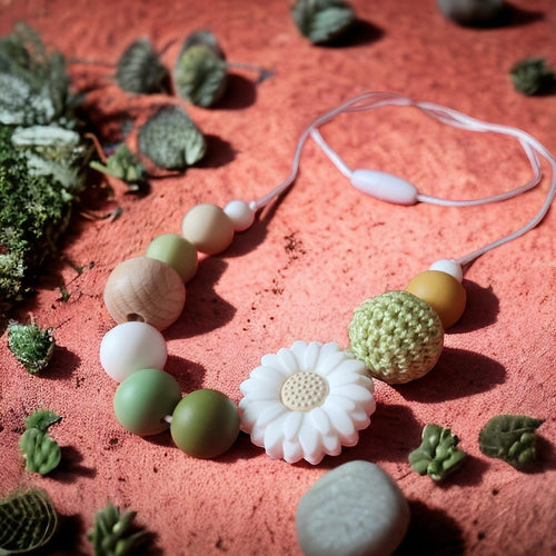 Precious Days Gifts handmade daisy teething necklace with silicone and wood beads in green, white, and tan.