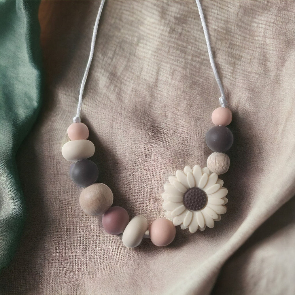 Precious Days Gifts daisy teething necklace with silicone and wood beads in pink, grey, and natural wood tones.
