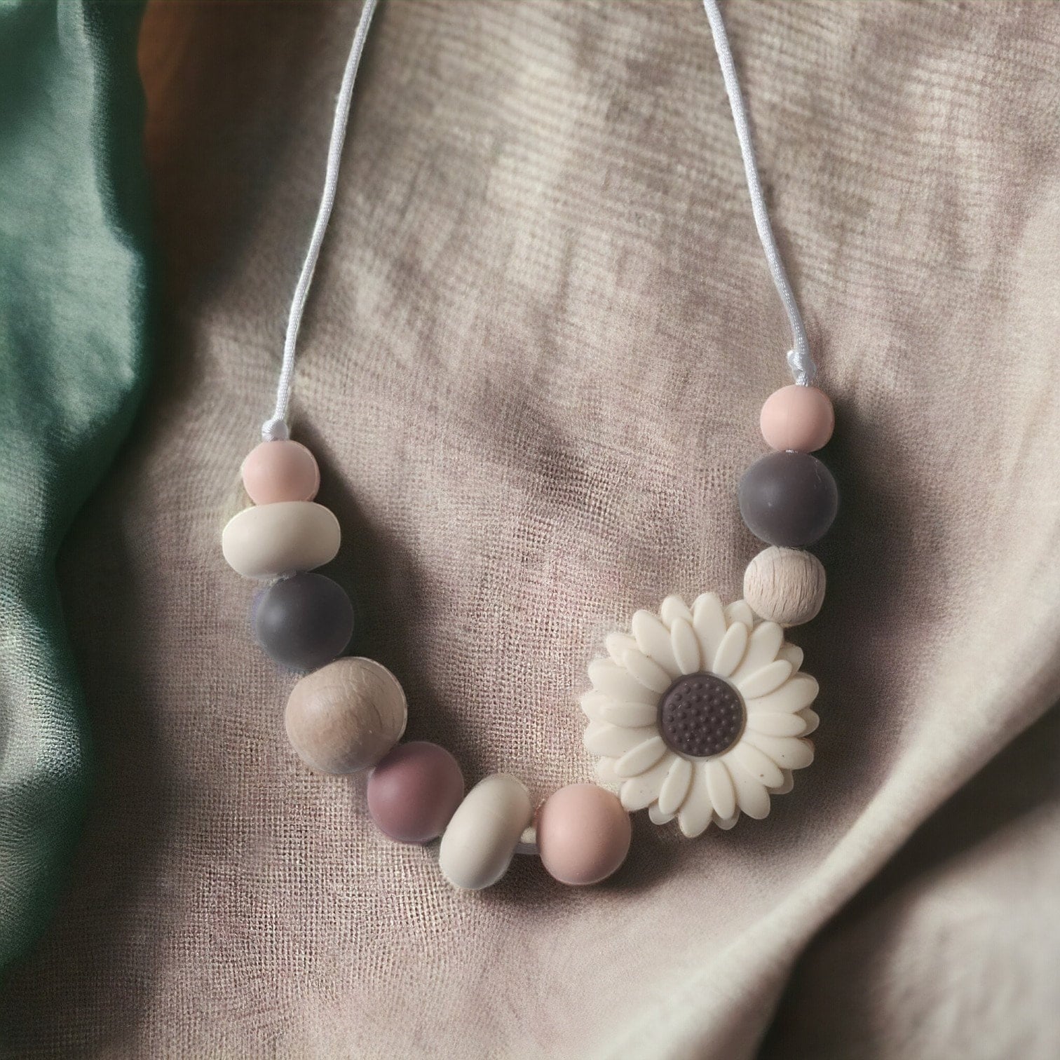 Precious Days Gifts daisy teething necklace with silicone and wood beads in pink, grey, and natural wood tones.