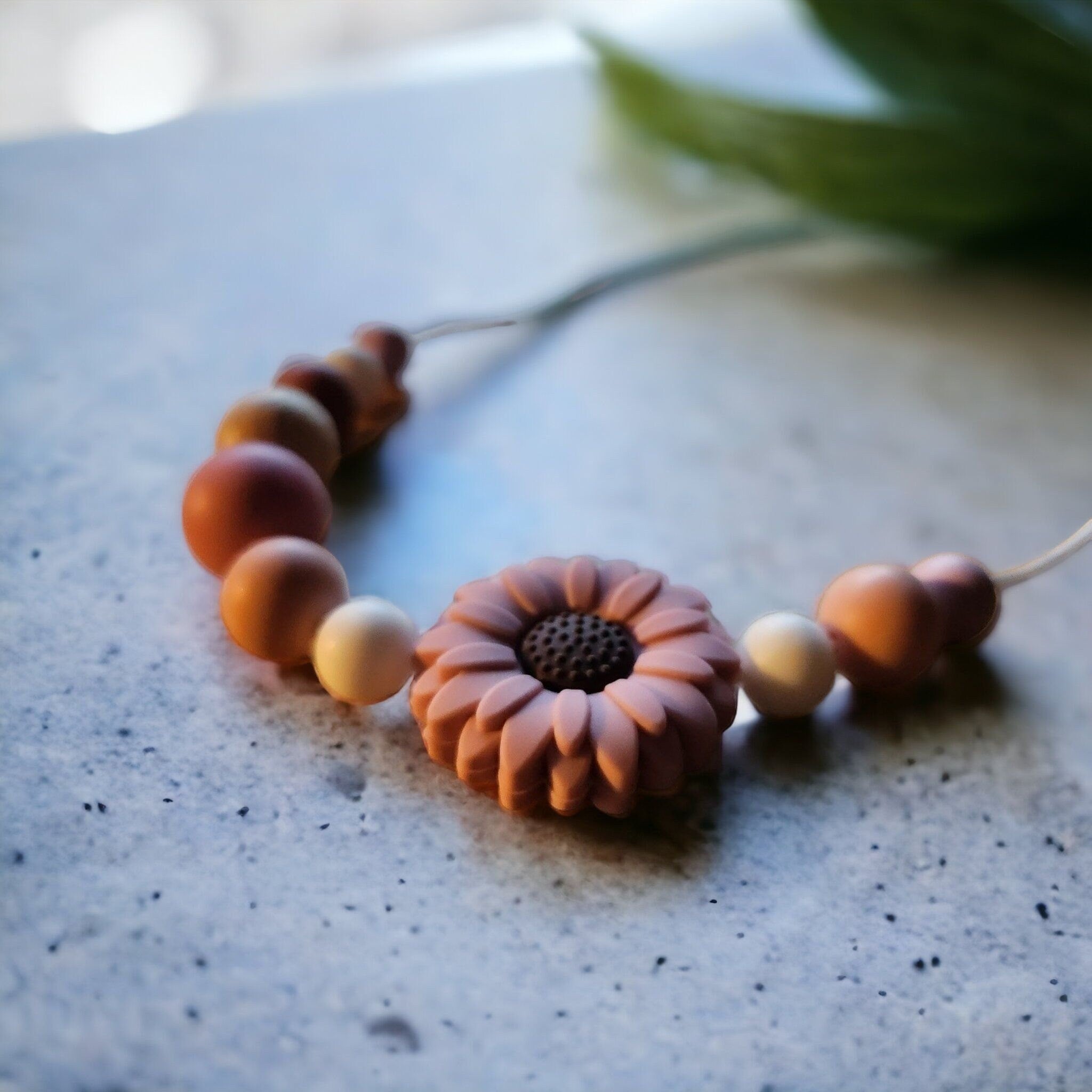 Precious Days Gifts daisy teething necklace with silicone and wood beads in terracotta and cream.