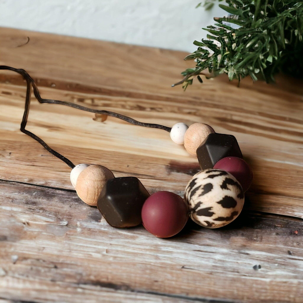 Precious Days Gifts dark animal print silicone and wood teething necklace with burgundy and black beads.
