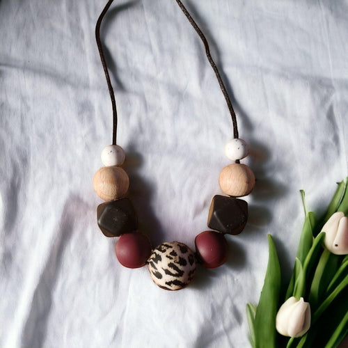 Precious Days Gifts dark animal print silicone and wood teething necklace with burgundy and dark brown beads.