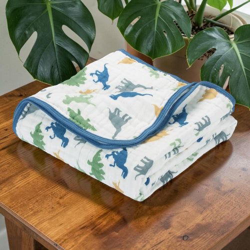 Precious Days Gifts large 120cm x 120cm 6-layer cotton muslin blanket with blue, green, and yellow dinosaur print and blue trim.