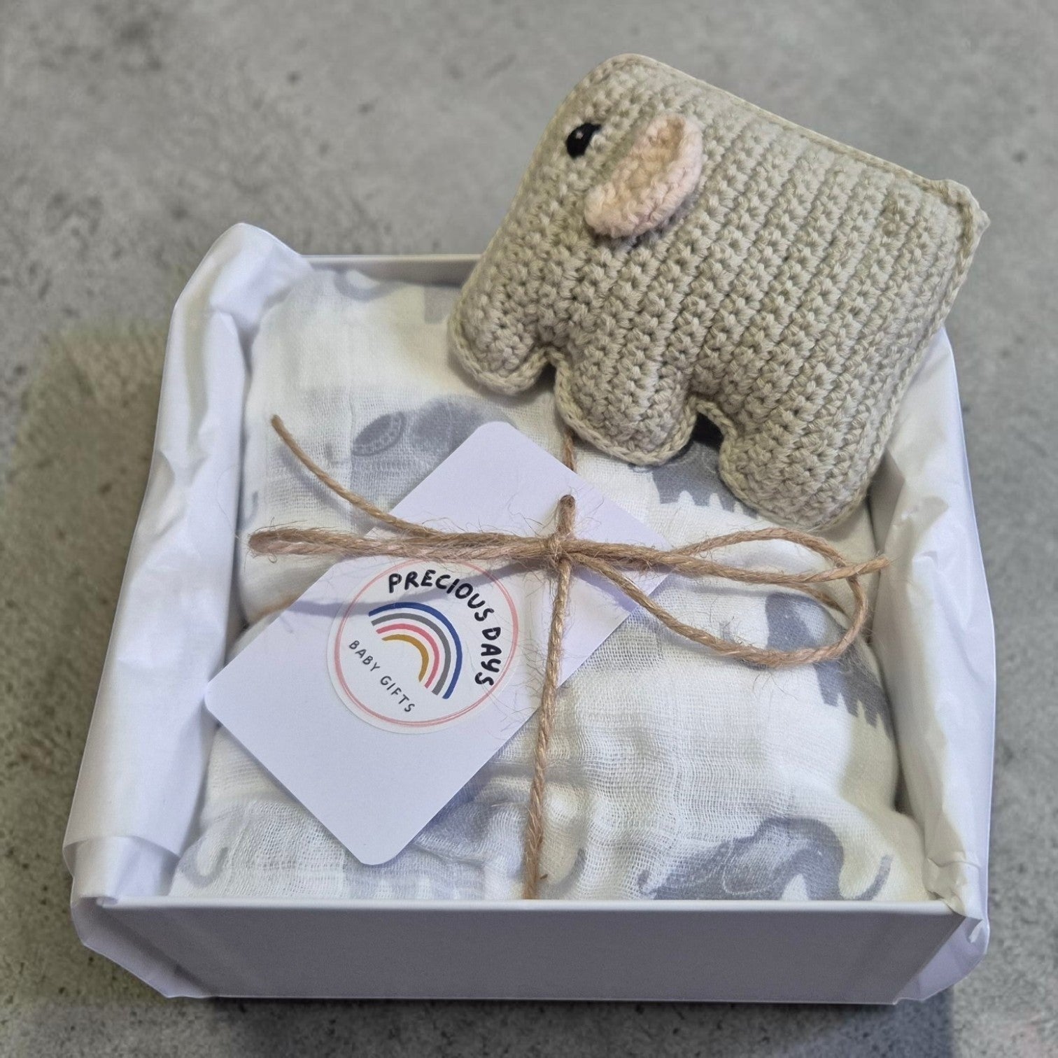 Precious Days Gifts baby gift box with elephant muslin, handmade crochet elephant rattle, and gift tag.