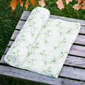 Precious Days Gifts 100% cotton muslin swaddle blanket with a relaxing green eucalyptus leaf print on white fabric.