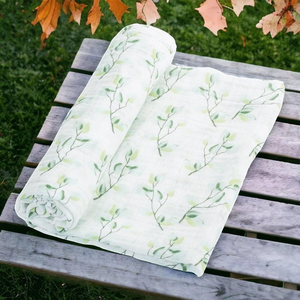 Precious Days Gifts eucalyptus muslin swaddle with a green leaf branch pattern, 100% cotton, 120cm x 120cm.