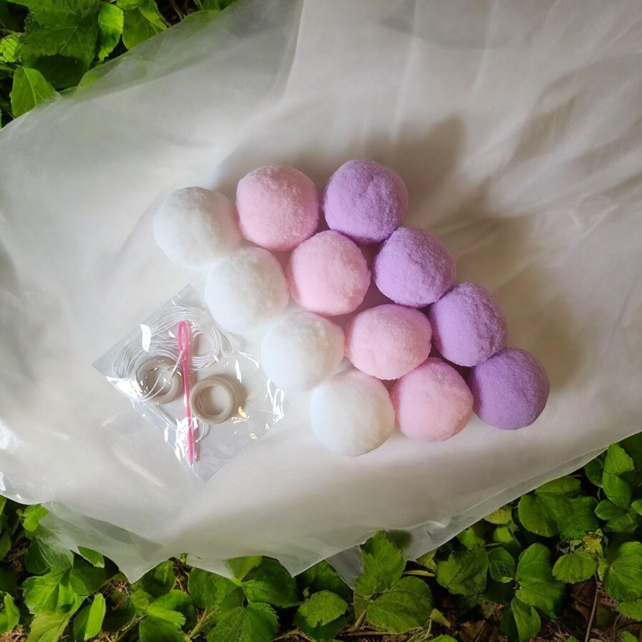 Precious Days Gifts Felt Ball Garland Craft Kit with white, pink, and lavender pom poms, string, needle, and wooden rings.