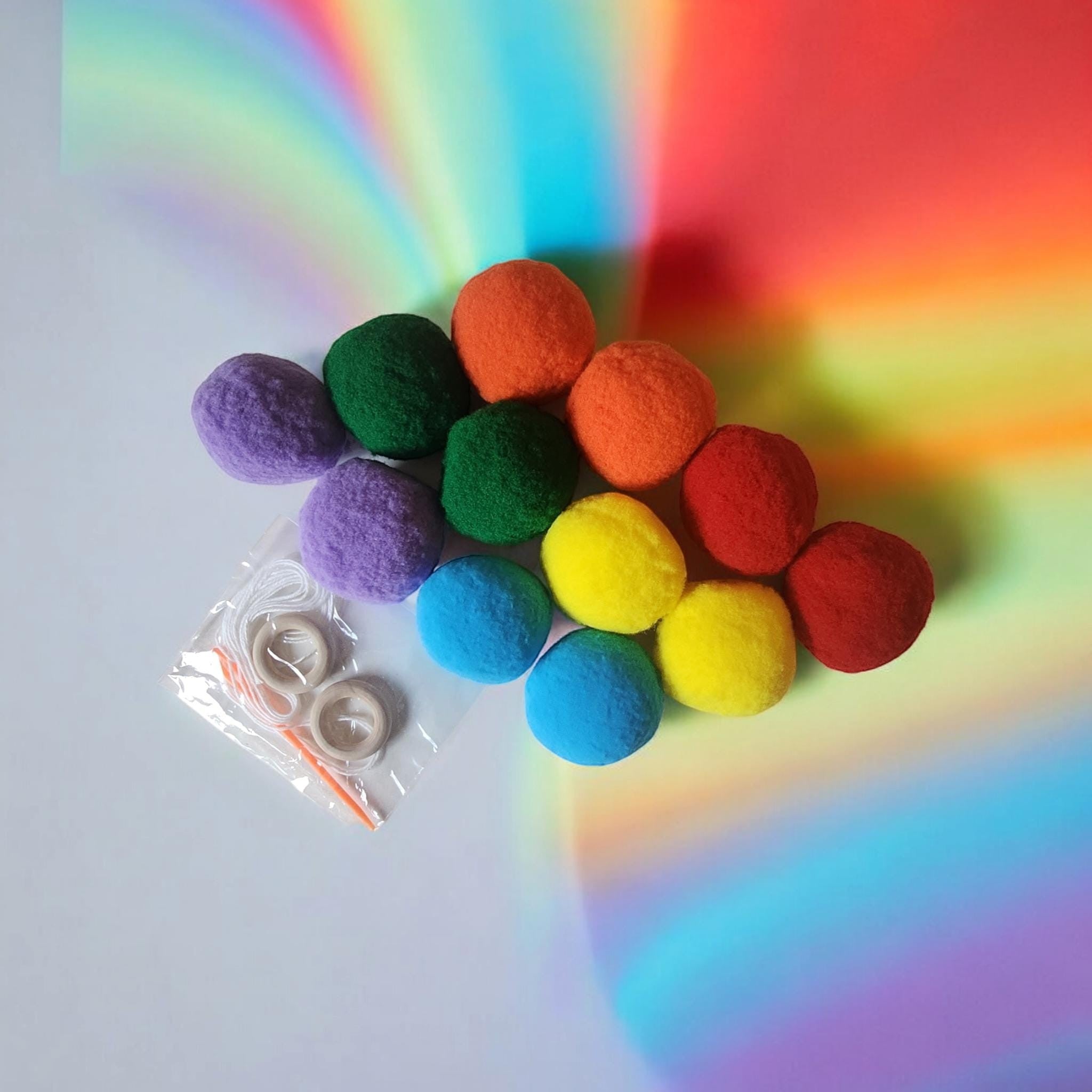 Precious Days Gifts Felt Ball Garland Craft Kit includes 12 colorful felt balls, string, and wooden rings for DIY decoration.