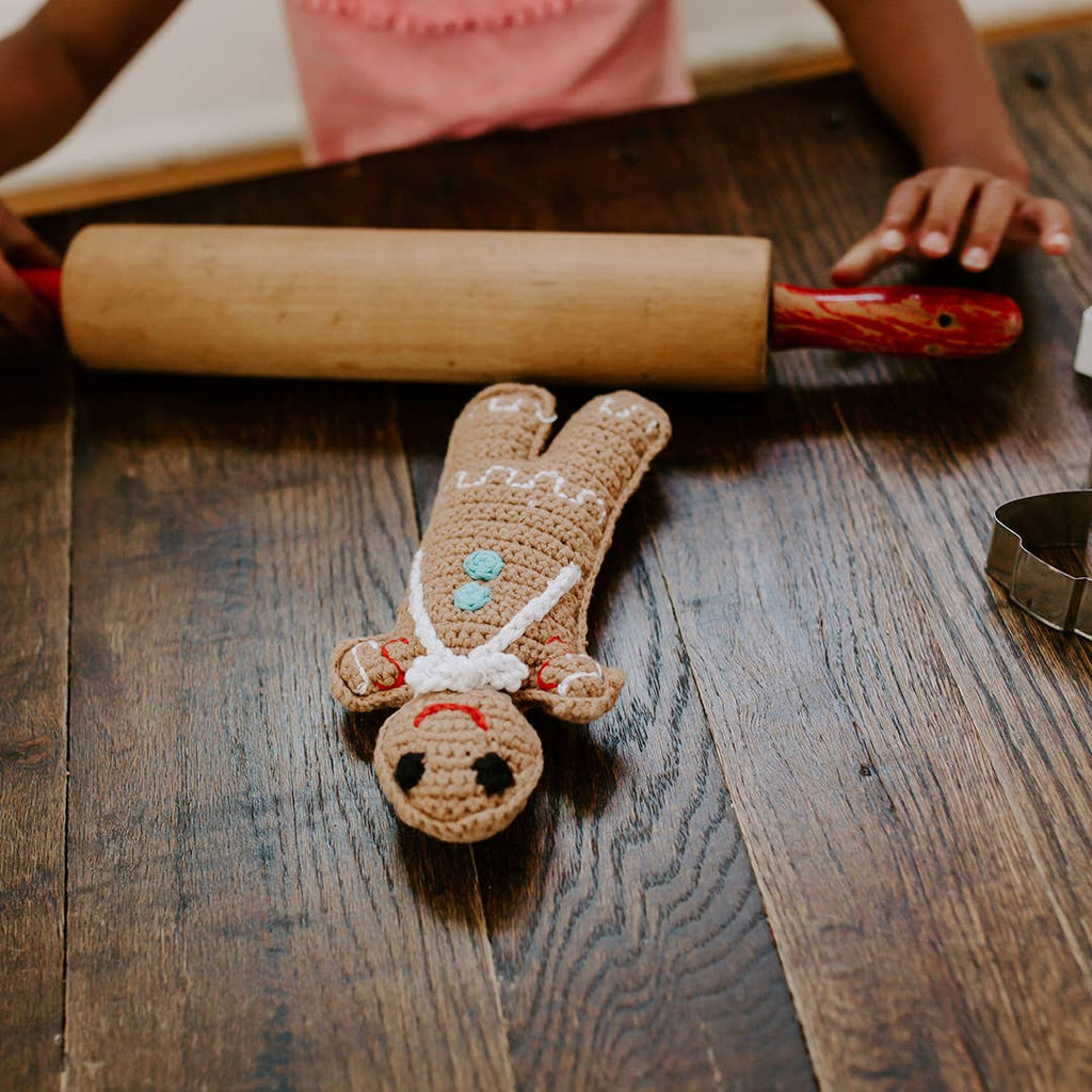 Precious Days Gifts handmade crocheted gingerbread man baby rattle with colourful buttons on a wooden table.