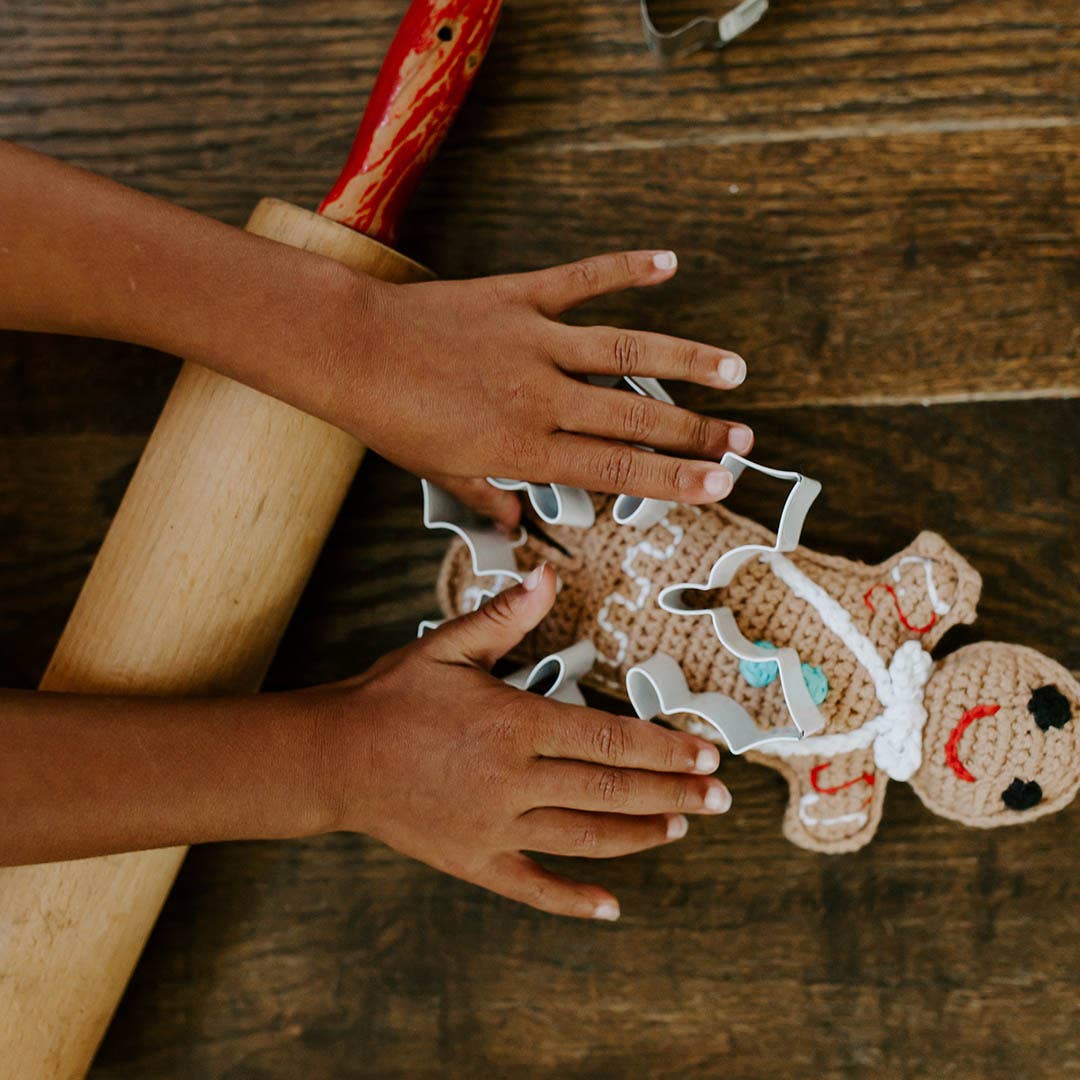 Precious Days Gifts handmade crochet gingerbread man rattle with colourful buttons on a wooden surface with a rolling pin