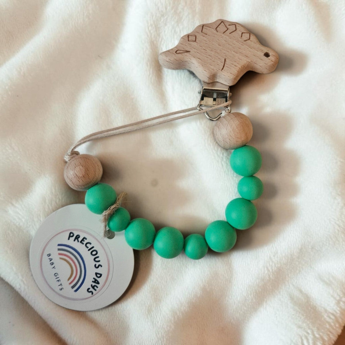 Precious Days Gifts wooden dinosaur dummy clip with green silicone beads and natural wood accents on white fabric