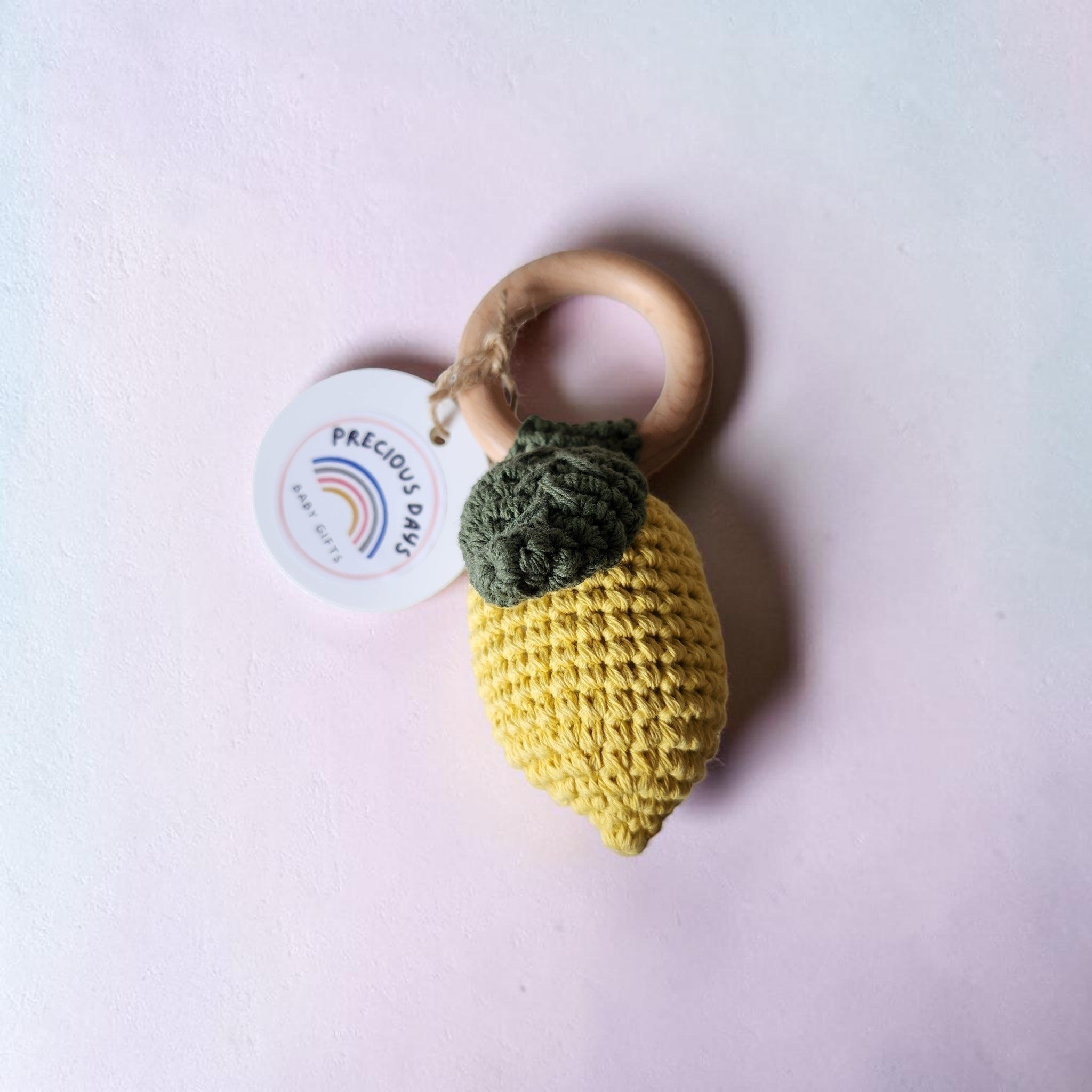 Precious Days Gifts handmade yellow lemon crochet baby rattle with a wooden ring handle and green textured leaves.