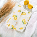 Precious Days Gifts 100% cotton muslin baby swaddle blanket with yellow lemon print on a white background