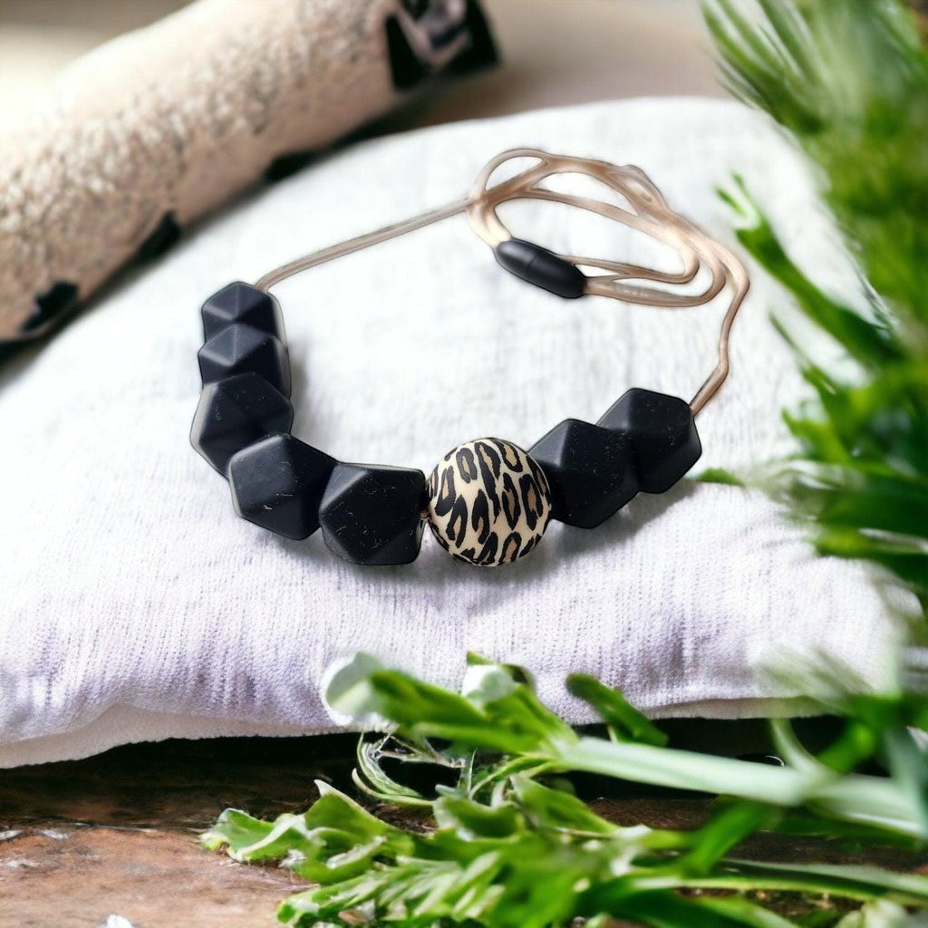 Precious Days Gifts Midnight Leopard silicone teething necklace with black faceted beads and a leopard print center bead.