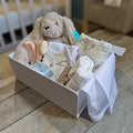 Precious Days Gifts luxury new baby gift box containing a plush bunny, cotton muslin, onesie, soap, and grooming set.