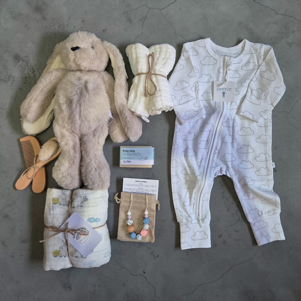 Precious Days Gifts luxury new baby gift box containing a bunny toy, cloud onesie, muslin cloths, and baby essentials.