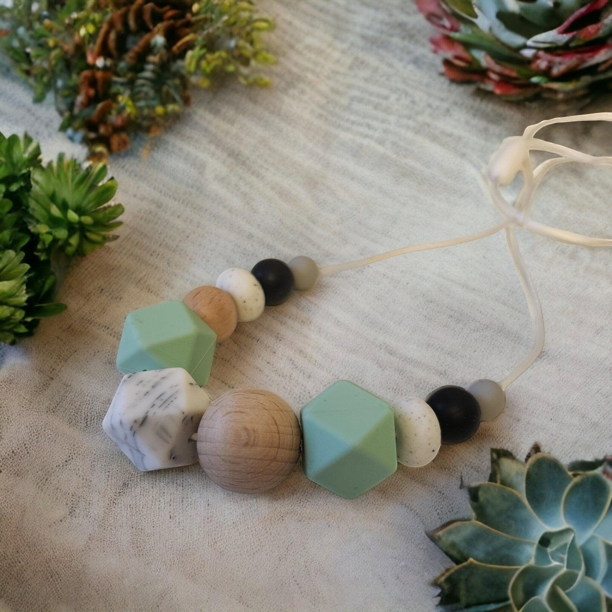 Precious Days Gifts mint green silicone and natural wood teething necklace with marble and black beads.