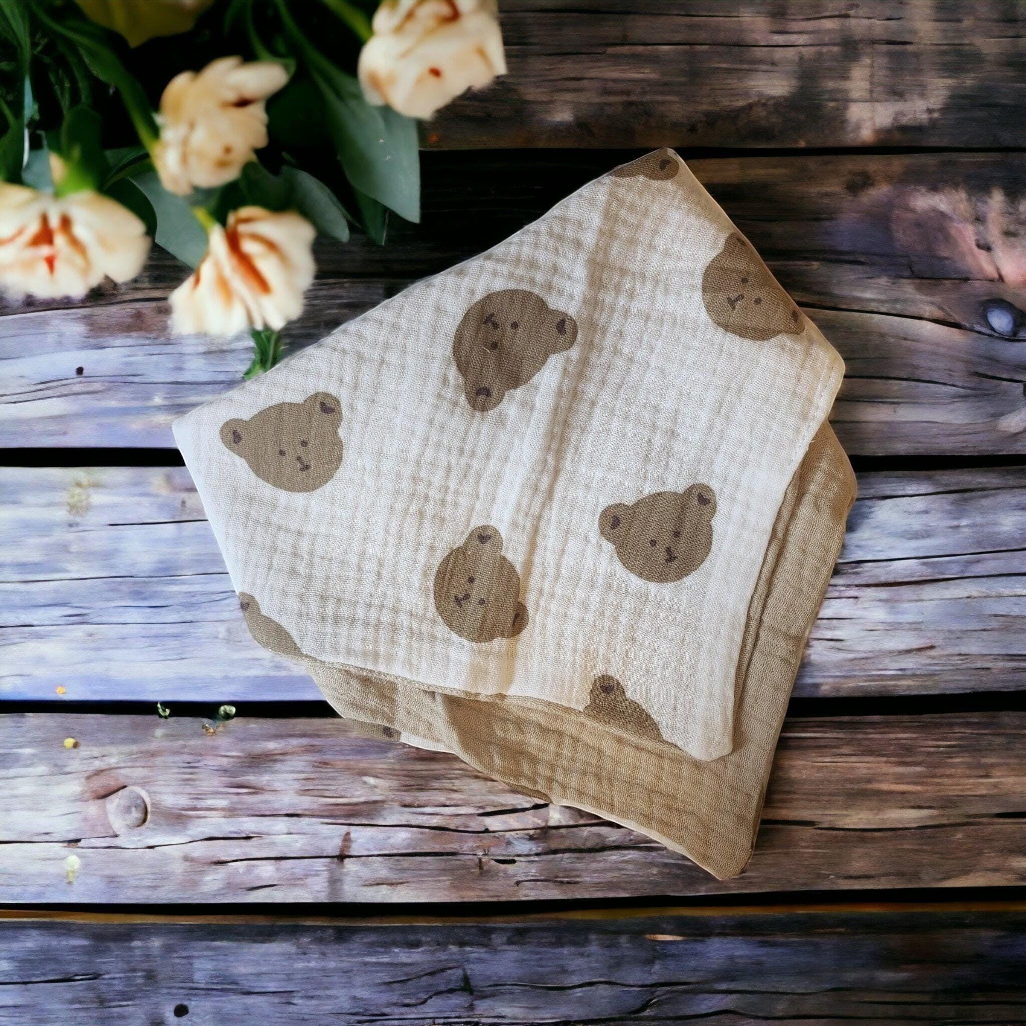 Precious Days Gifts soft muslin cotton baby bib with a cute teddy bear pattern in brown on a cream background.