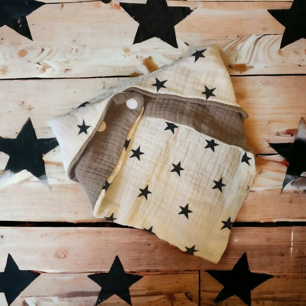 Precious Days Gifts bandana bib in cream muslin with black stars and a brown band. Features snap closure.
