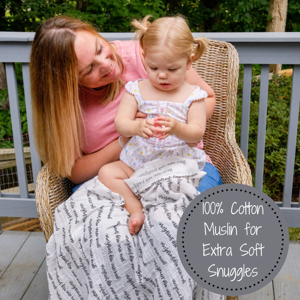Precious Days Gifts You Are My Sunshine muslin swaddle blanket covering a mother and toddler sitting in a wicker chair