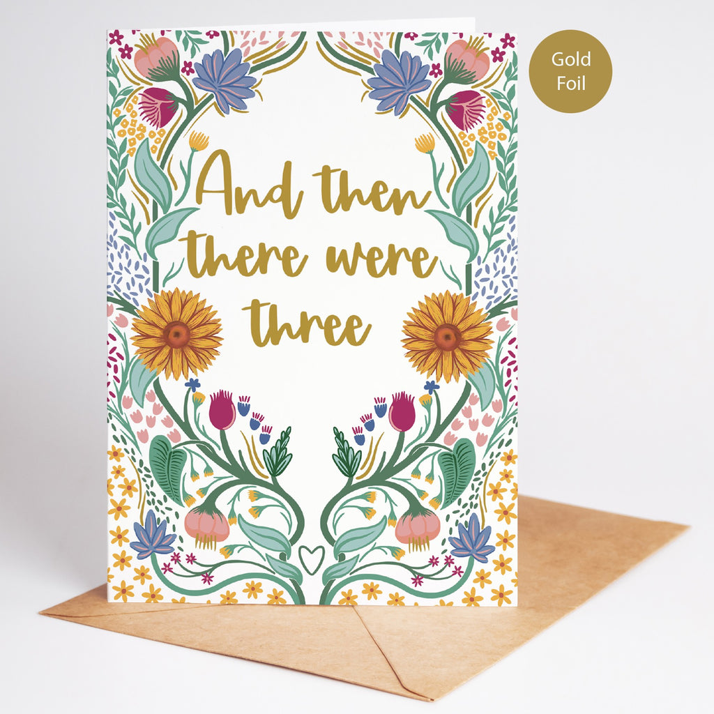 Precious Days Gifts new baby card with gold foil lettering reading "And then there were three" surrounded by folk-inspired florals.