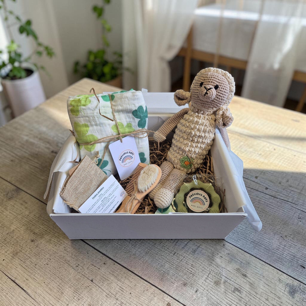 Precious Days Gifts Signature Belfast Box with shamrock muslin, crochet sheep rattle, teething ring, and baby brush.