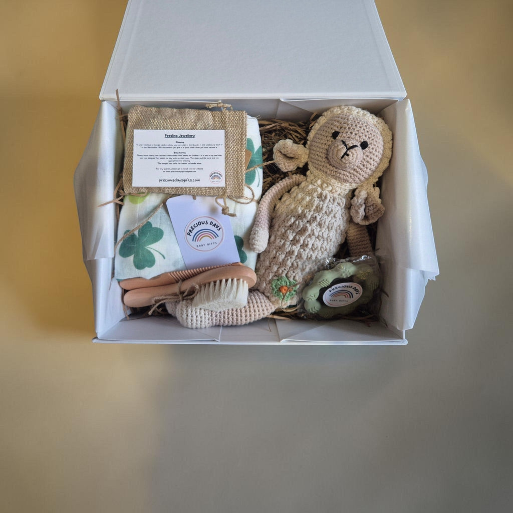 Precious Days Gifts Signature Belfast Box featuring a shamrock muslin, crochet sheep rattle, and baby grooming set.