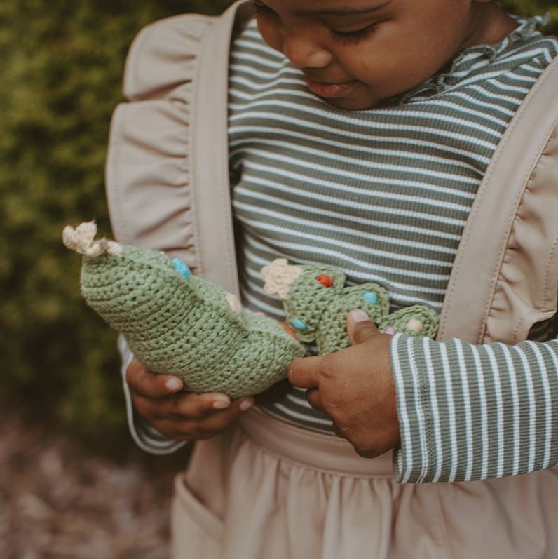 Precious Days Gifts organic cotton crochet Christmas tree rattle held by a child in a striped shirt