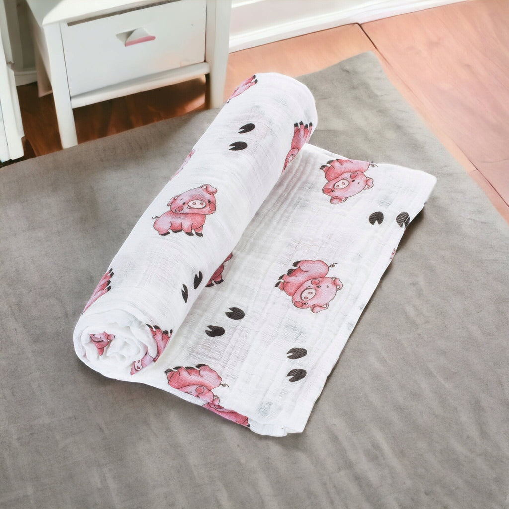 Precious Days Gifts white 100% cotton muslin swaddle with a pink pig and hoof print pattern.