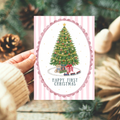 Precious Days Gifts pink A6 first Christmas card with hand-illustrated tree, teddy bear, and gifts in scalloped oval
