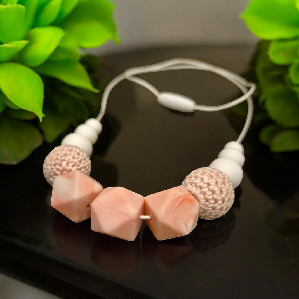 Precious Days Gifts pink and white silicone teething necklace with textured beads and a breakaway clasp.