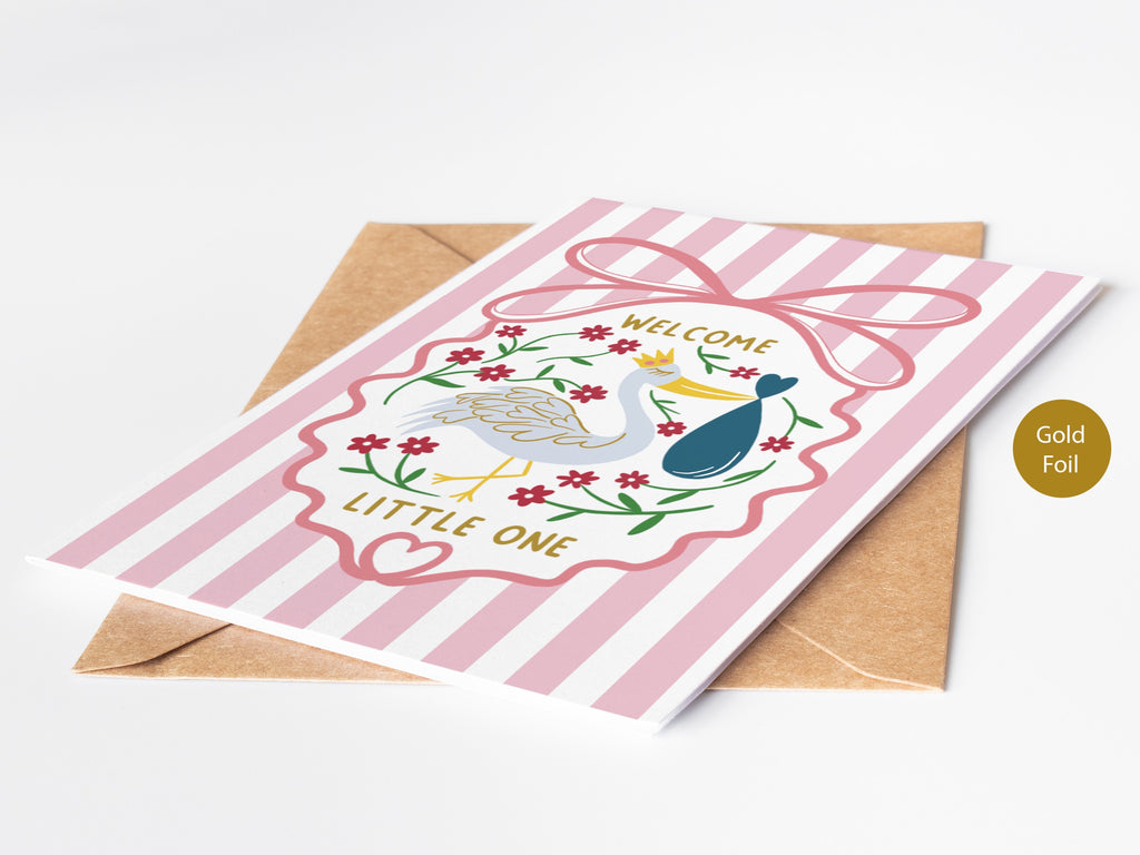 Precious Days Gifts pink striped baby card with stork, floral wreath, and gold "Welcome Little One" lettering.